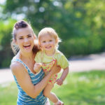 Smiling mother and baby playing in park